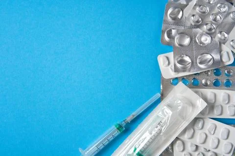 Empty used blisters from tablets silver and white color and pills lie on blue Foto stock