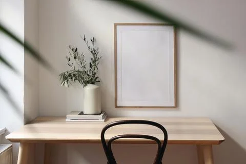Empty vertical picture frame mockup. Wooden desk, table. Vase with olive Stock-Fotos