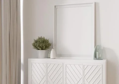 Empty vertical picture frame standing on white sideboard. Mock up interior in Stock Photos