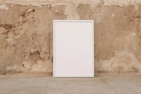 Empty vertical white thin picture frame, poster mockup. Beige textured sandstone 写真素材