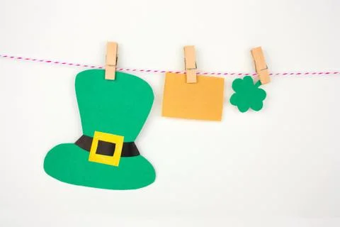 Empty vintaage paper note, paper hat and shamrock leaf on clothespin on white Stock-Fotos
