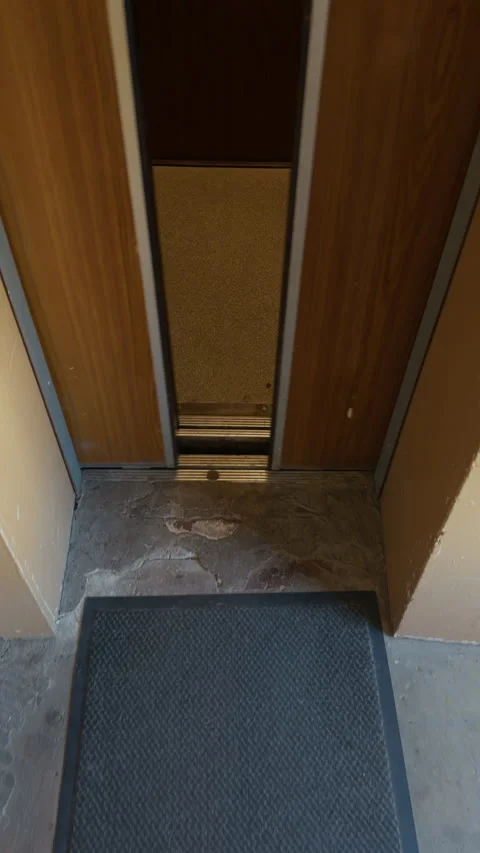 Empty vintage elevator interior with worn floor, metal threshold, and dim wood Stock Footage 342502665