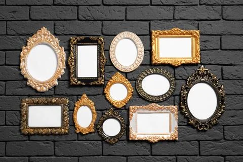 Empty vintage frames hanging on dark brick wall. Mockup for design Stock Photos