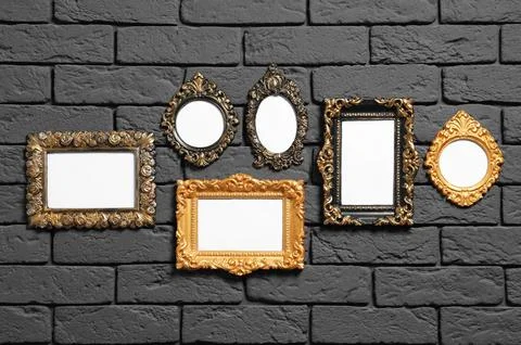 Empty vintage frames hanging on dark brick wall. Mockup for design Stock Photos