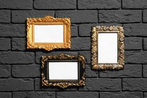 Empty vintage frames hanging on dark brick wall. Mockup for design Stock Photos