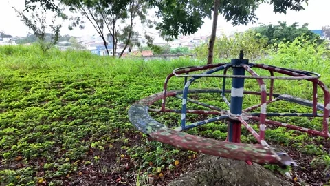 Empty vintage merry-go-round spinning alone in an overgrown abandoned park. Stockbeeldmateriaal 334061153