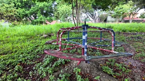 Empty vintage merry-go-round spinning alone in an overgrown abandoned park. 스톡 동영상 334061158