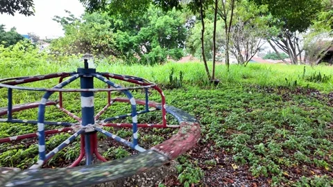 Empty vintage merry-go-round spinning alone in an overgrown abandoned park. 스톡 동영상 334061165