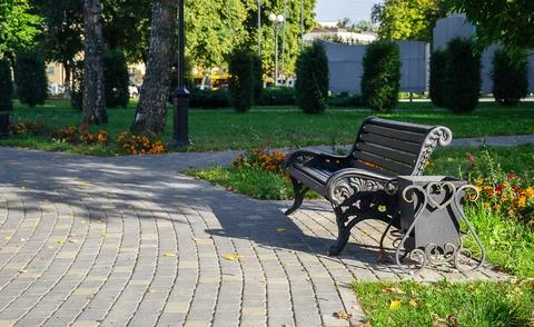 Empty vintage style park bench and metal waste bin on tiled pavement of outdoor Stock Photos