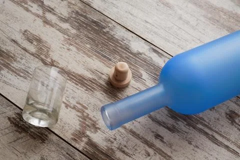Empty vodka bottle on the table next to a shot glass and cork Foto stock