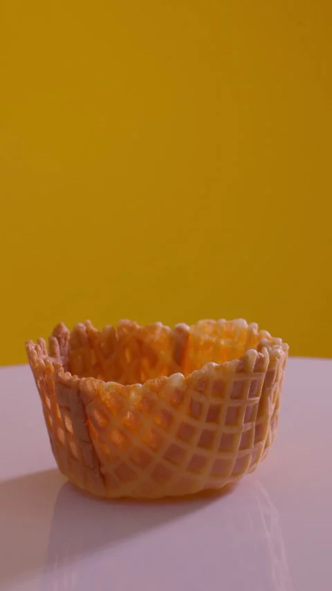 Empty waffle cup rotating on yellow background. Vertical close-up shot Stock Footage 314553883