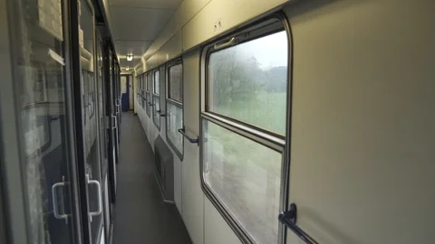 Empty wagon aisle on a train passing through the countryside in rainy weather Stock Footage 115766310