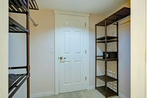 Empty walk in closet features clothes racks and metal shelving units. Stock Photos