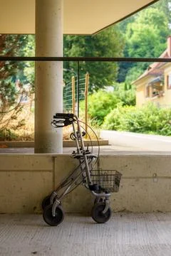 An empty walker for the elderly parked against a concrete wall outdoors Stock Photos