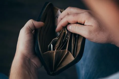 An empty wallet with a small amount of money in the hands of a working man. P Stock Photos