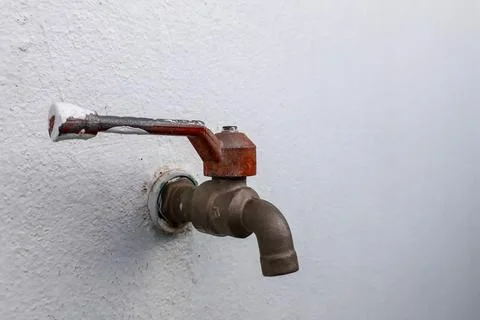 The empty water tap next to the wall shows the drought. Stock-Fotos