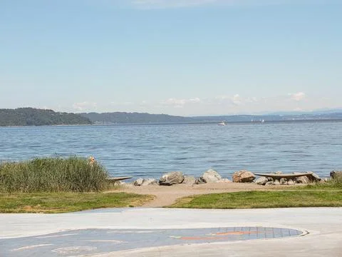 Empty waterfront promenade with a concrete square and stone boulders on the b Stockfoto's