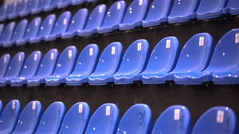 Empty wet blue chairs on the tribune of a football stadium under a rain Stock Footage