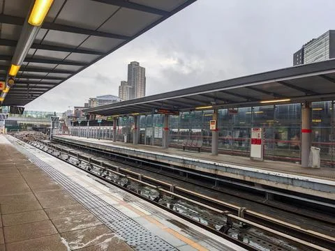 An empty, wet platform and tracks at Stratfords modern DLR station under Stock Photos