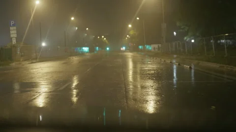 Empty wet road at night with glowing streetlights, misty air, and reflective Stock Footage 345531617