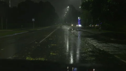 Empty wet road at night with storm debris, rain reflections and dim street Stock Footage 345530465