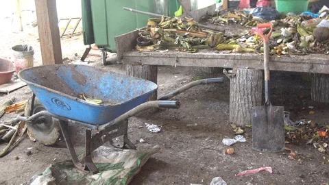 Empty wheelbarrow for transportation of garbage. standing near a pile of waste Stock Footage 127047314