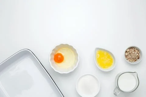 Empty white baking dish with ingredients for baking, including egg, milk, but Stock Photos