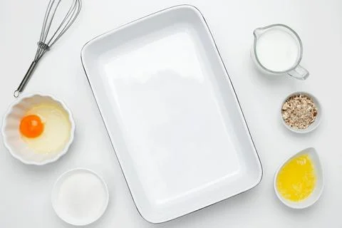 Empty white baking dish with ingredients for baking, including egg, milk, but Stock Photos