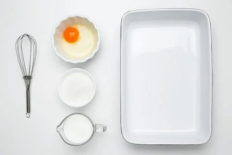 Empty white baking dish with ingredients for baking, including egg, milk, but Stock Photos