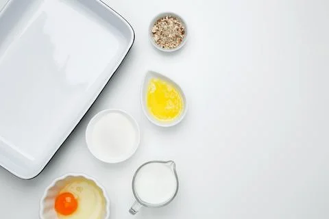 Empty white baking dish with ingredients for baking, including egg, milk, but Stock Photos
