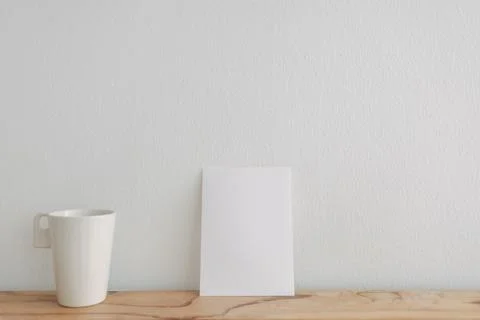Empty white card mockup lean on a tea cup with white wall. Stock-Fotos