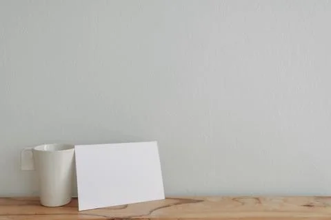 Empty white card mockup lean on a tea cup with white wall. Stockfoto's