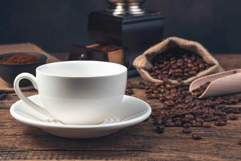 An empty white ceramic cup against the background of coffee beans and a coffe Stock Photos