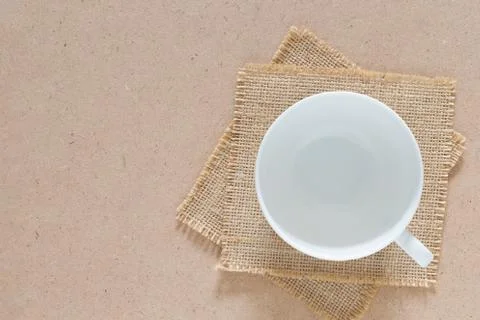 Empty white ceramic cup of coffee was placed on burlap cloth on craft board. Stock-Fotos