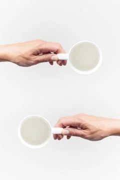 An empty white ceramic cups in a female hands on a white background, food moc Stock Photos