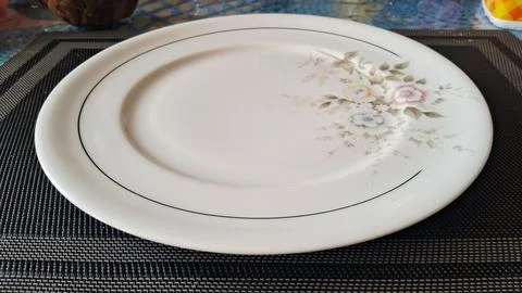 Empty white ceramic dinner plate. Elegant porcelain dish with floral pattern for Stock Photos