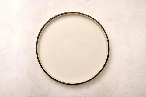 Empty white ceramic plate with black rim on a light textured background Foto stock