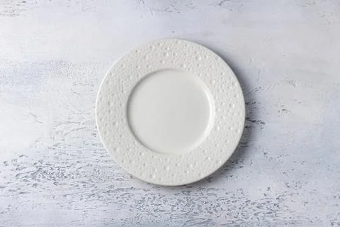Empty white ceramic plate on light textured background, top view for food m.. Stock Photos