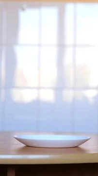 Empty White Ceramic Plate Standing on Wooden Table on Blurred Light Stock Photos