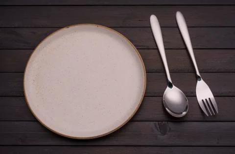 Empty white ceramic plates with spoons and forks arranged on an old black woo Stock Photos