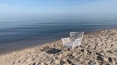 An empty white chair left on white sand shore of the Baltic sea. Zen-like. Stock Footage