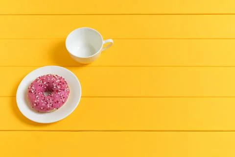 Empty White Coffee Cup and Pink Glazed Donut on a Yellow Wooden Background Stock Photos