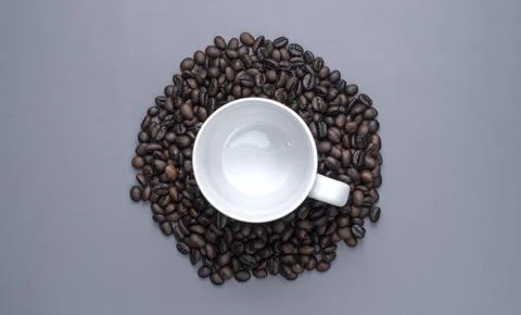 Empty White Coffee Cup Surrounded by Roasted Beans on Gray Background Stock Photos