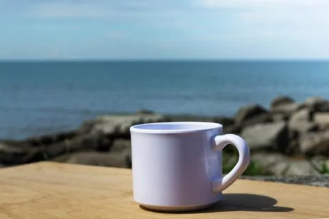 Empty white cup on blurred beach background Stock Photos