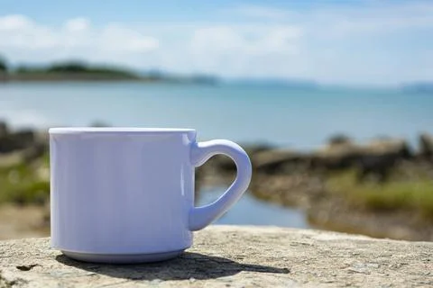Empty white cup on blurred beach background Stock Photos