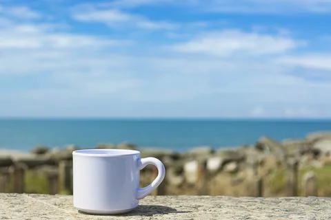 Empty white cup on blurred beach background Foto stock