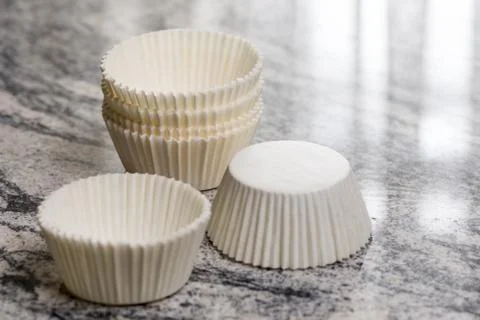 Empty white cup cake cases containers on the grey granite marble background Stock Photos