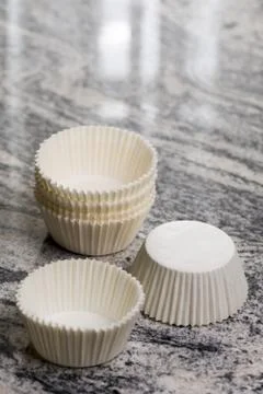 Empty white cup cake cases containers on the grey granite marble background Stock Photos