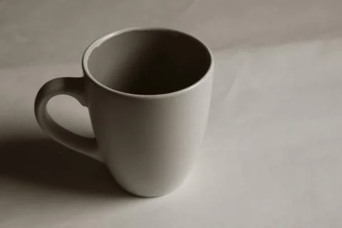 Empty white cup on a light background. Cup with place for text. Copyspace. Stock Photos