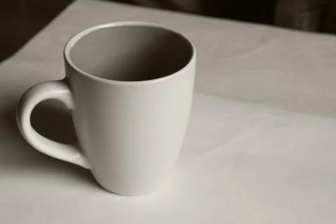 Empty white cup on a light background. Cup with place for text. Copyspace. Stock Photos